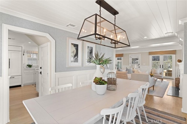 dining area featuring visible vents, wooden ceiling, a wainscoted wall, light wood-style floors, and a decorative wall