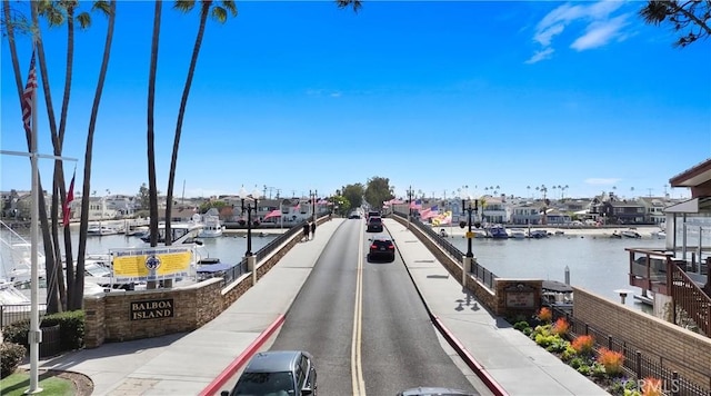 view of road featuring a water view, sidewalks, and curbs