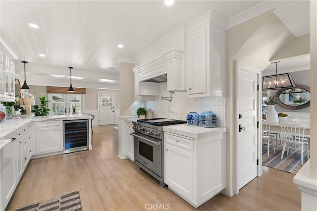 kitchen featuring wine cooler, white cabinets, hanging light fixtures, tasteful backsplash, and stainless steel range