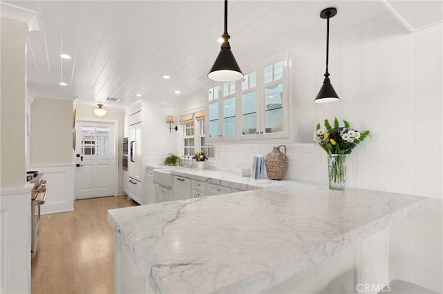 kitchen featuring decorative light fixtures, a decorative wall, glass insert cabinets, white cabinets, and a peninsula