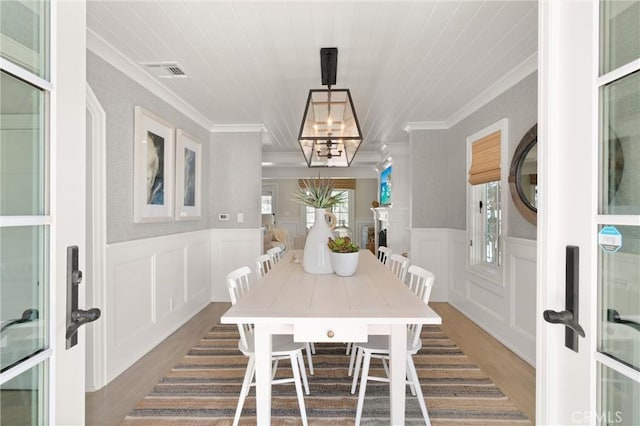 dining area with crown molding, wood finished floors, visible vents, and an inviting chandelier