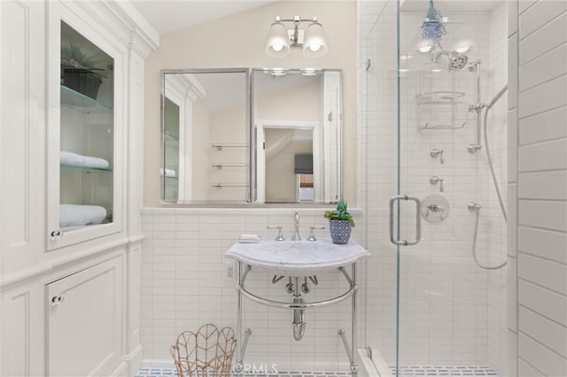 full bath featuring lofted ceiling, a stall shower, and tile walls