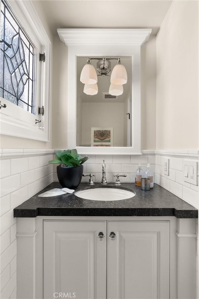 bathroom with wainscoting, vanity, and tile walls