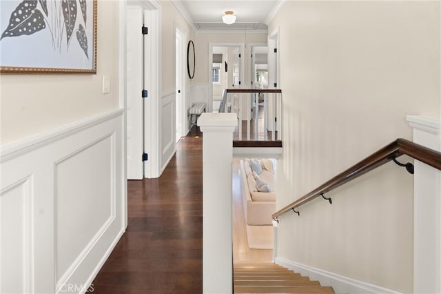 hall featuring attic access, dark wood-style flooring, crown molding, an upstairs landing, and a decorative wall