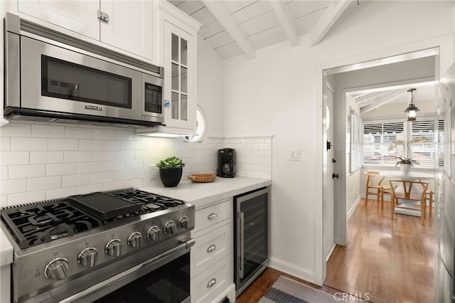 kitchen featuring white cabinets, lofted ceiling with beams, wine cooler, glass insert cabinets, and appliances with stainless steel finishes