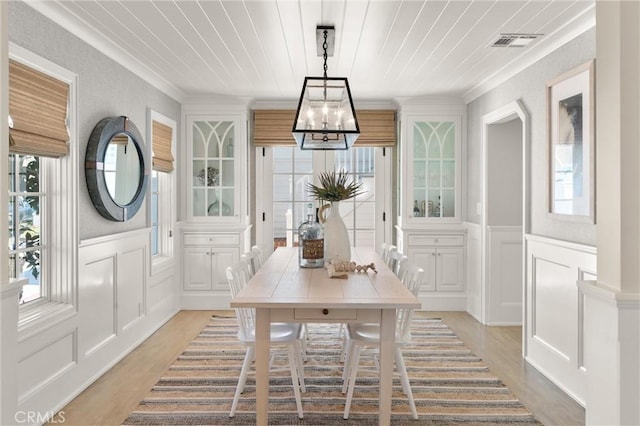 dining area featuring plenty of natural light, visible vents, light wood-style flooring, and a decorative wall