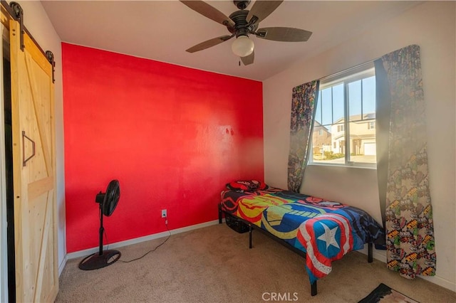 carpeted bedroom featuring ceiling fan, a barn door, and baseboards