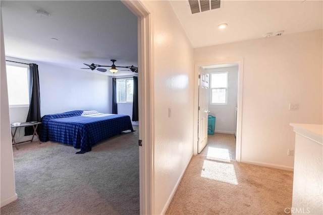 bedroom with light colored carpet, ceiling fan, visible vents, and baseboards