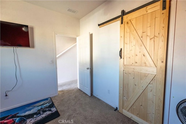 interior space featuring a barn door, carpet, visible vents, and baseboards