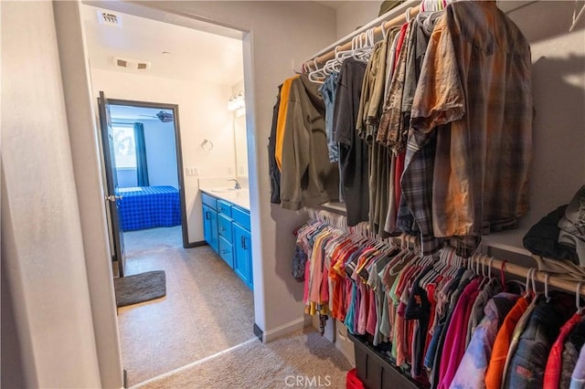 walk in closet with light colored carpet, visible vents, and a sink