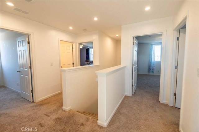 corridor featuring visible vents, baseboards, light colored carpet, an upstairs landing, and recessed lighting