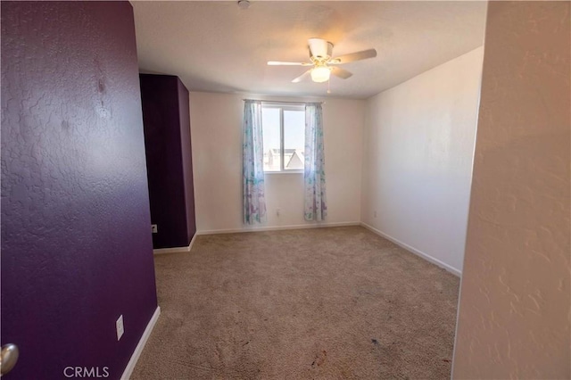 empty room featuring baseboards, a ceiling fan, and light colored carpet