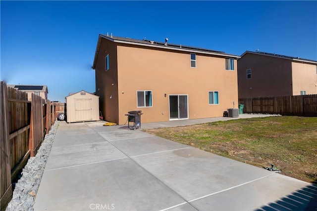 rear view of house with a patio, a fenced backyard, a storage shed, an outdoor structure, and stucco siding