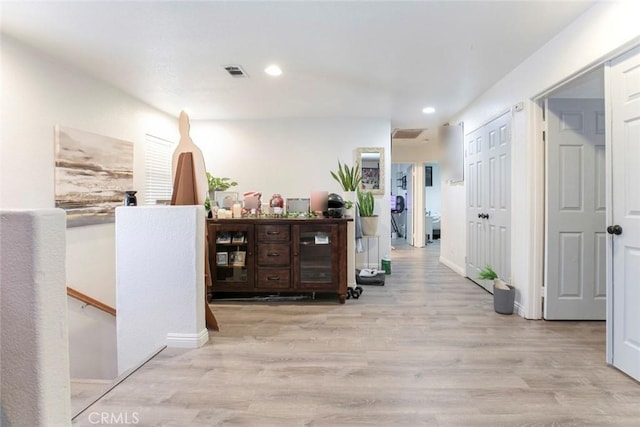 hallway with recessed lighting, visible vents, wood finished floors, and an upstairs landing