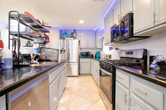 kitchen featuring recessed lighting, appliances with stainless steel finishes, light tile patterned flooring, a sink, and dark stone counters