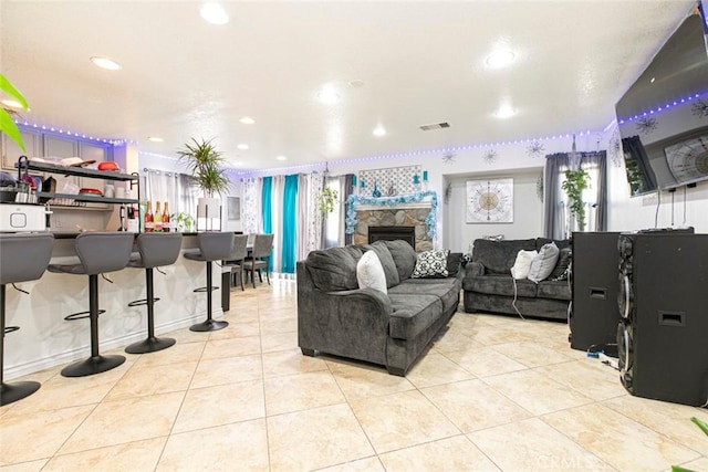 living room featuring light tile patterned floors, a stone fireplace, visible vents, and recessed lighting