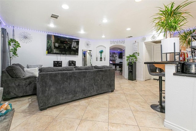 living area with arched walkways, recessed lighting, visible vents, light tile patterned flooring, and baseboards