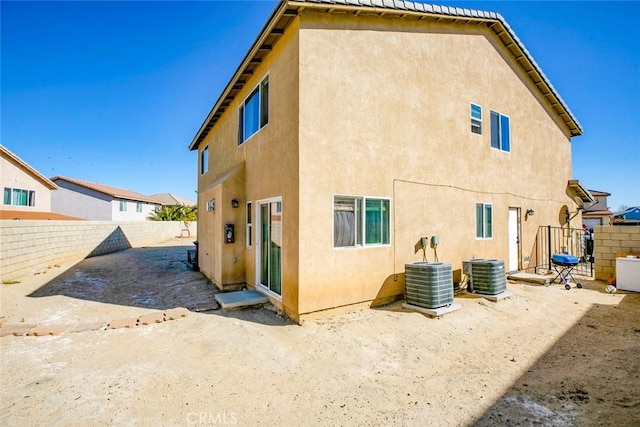 rear view of property with a fenced backyard, cooling unit, and stucco siding