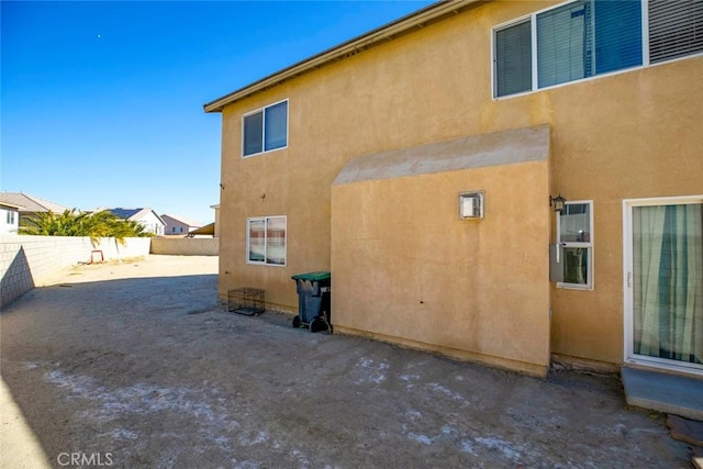 view of side of home with a patio area, a fenced backyard, and stucco siding