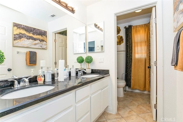 bathroom featuring double vanity, a sink, toilet, and tile patterned floors