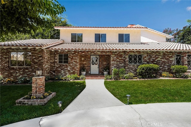 view of front of property featuring brick siding, a front lawn, and a tiled roof