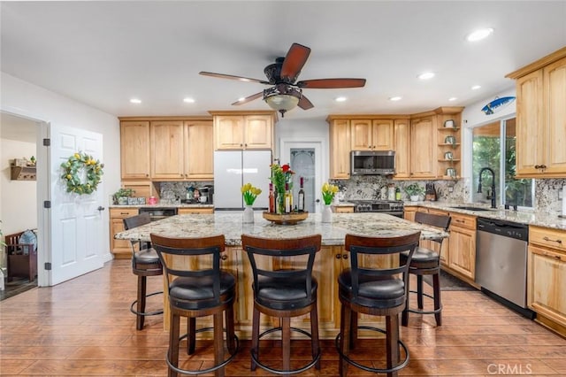 kitchen with stainless steel appliances, a center island, a breakfast bar area, and open shelves