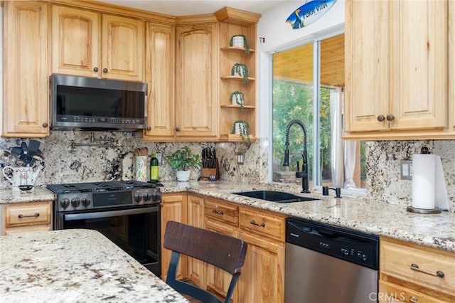 kitchen featuring light stone counters, appliances with stainless steel finishes, a sink, open shelves, and backsplash