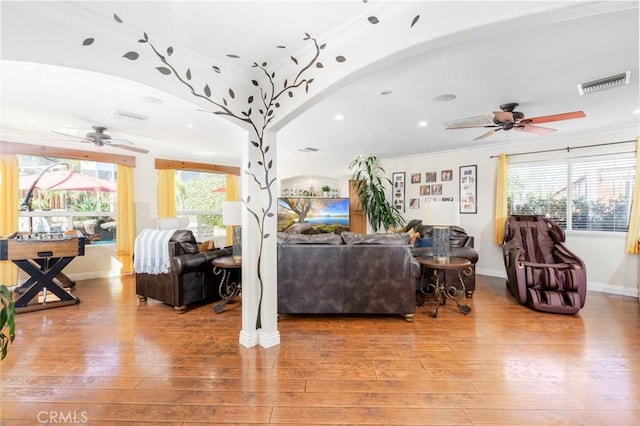 living area with baseboards, visible vents, ceiling fan, ornamental molding, and light wood-type flooring