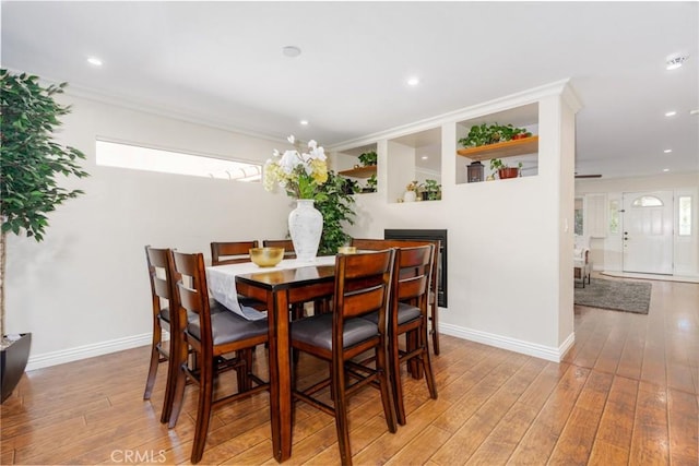 dining room featuring ornamental molding, light wood-type flooring, and baseboards