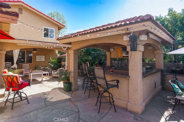 view of patio with a bar, an outdoor hangout area, and a ceiling fan