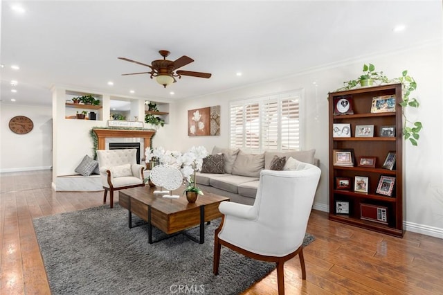 living area with dark wood-style floors, crown molding, a fireplace, and baseboards