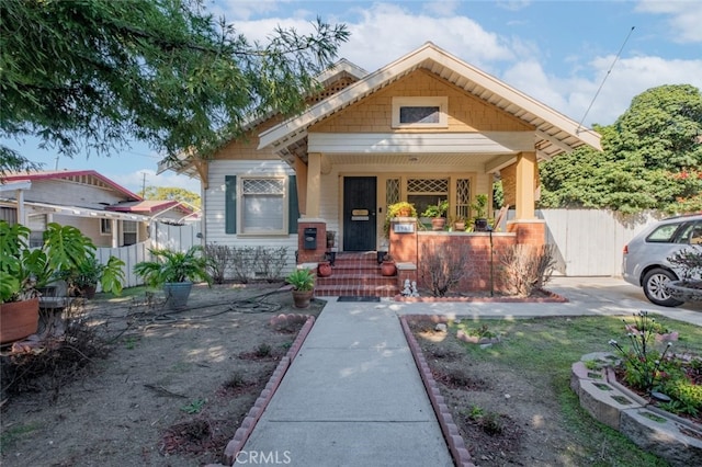 bungalow-style house featuring covered porch and fence