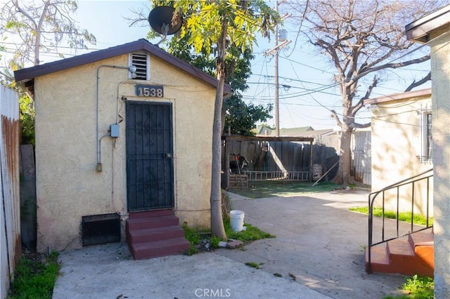 view of outbuilding featuring entry steps, an outdoor structure, and fence