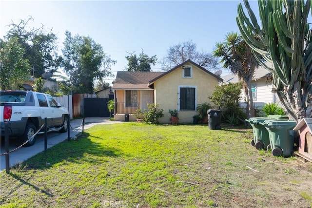 view of front facade with a front yard, fence, a porch, and stucco siding