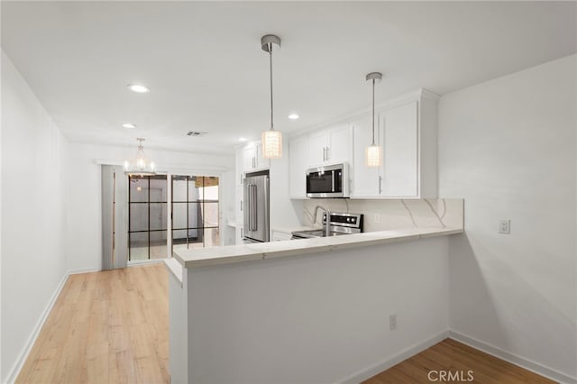 kitchen featuring light wood finished floors, decorative backsplash, appliances with stainless steel finishes, light countertops, and white cabinetry