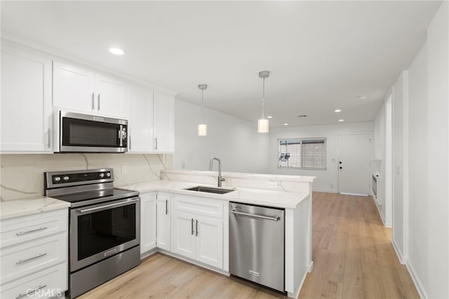 kitchen with stainless steel appliances, tasteful backsplash, white cabinetry, a sink, and a peninsula