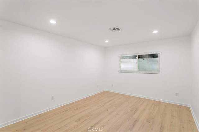 spare room featuring light wood finished floors, baseboards, visible vents, and recessed lighting