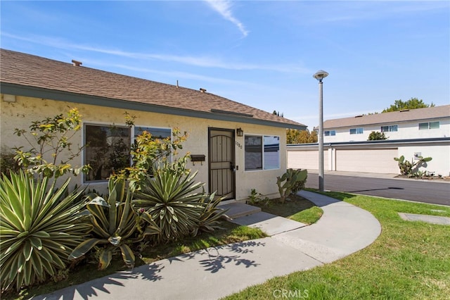 view of front of home featuring a shingled roof and stucco siding