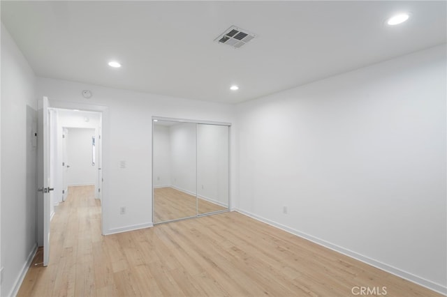 unfurnished bedroom featuring recessed lighting, a closet, visible vents, and light wood finished floors