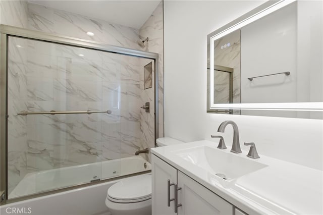 bathroom featuring combined bath / shower with glass door, vanity, and toilet