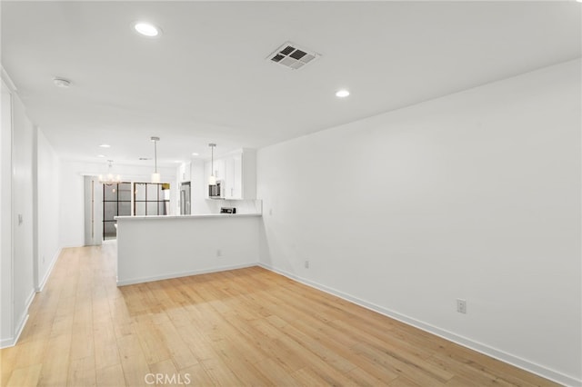 unfurnished living room featuring light wood-style floors, visible vents, a chandelier, and recessed lighting