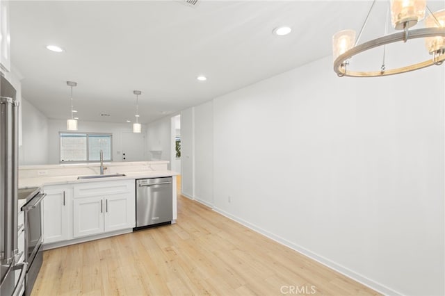 kitchen featuring range, dishwasher, light wood finished floors, and a sink