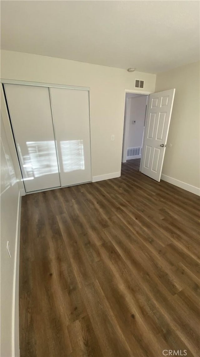 unfurnished bedroom featuring dark wood-type flooring, visible vents, and baseboards