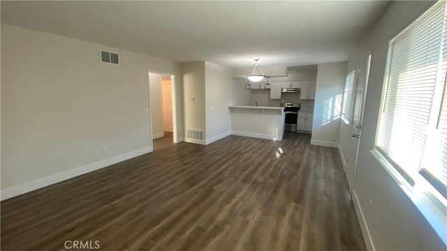 unfurnished living room with baseboards, visible vents, and dark wood finished floors