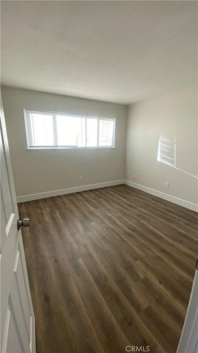 empty room with dark wood-style floors and baseboards