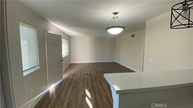 unfurnished dining area featuring baseboards, visible vents, vaulted ceiling, and dark wood-type flooring