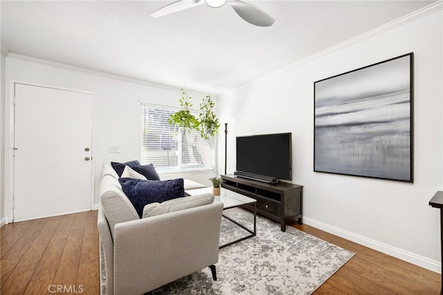 living room featuring baseboards, wood finished floors, a ceiling fan, and crown molding