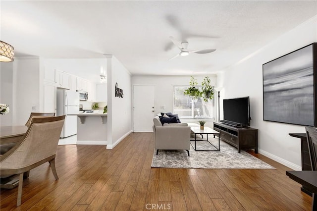 living room with light wood-style floors, baseboards, and a ceiling fan