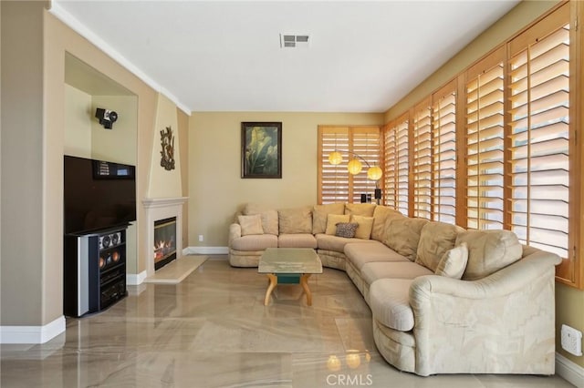 living area featuring a glass covered fireplace, visible vents, and baseboards