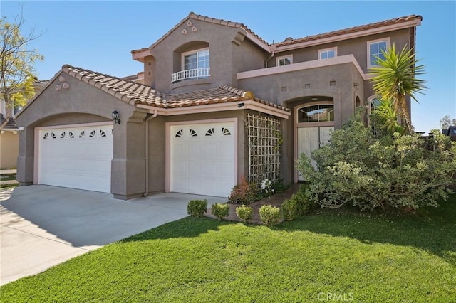 mediterranean / spanish house with driveway, a tile roof, a front yard, and stucco siding